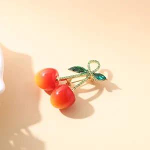 Vue détaillée d'une broche cerise scintillante avec finition en émail dégradé rouge