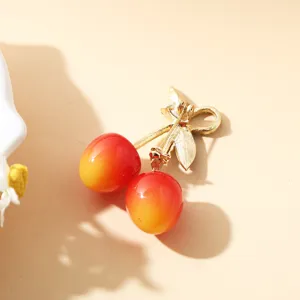 Vue arrière détaillée d'une broche cerise créative avec épingle dorée et fermoir sécurisé