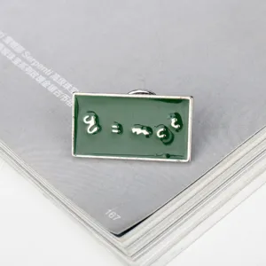 Detailed close-up of a green enamel pin featuring the E=mc² Einstein equation