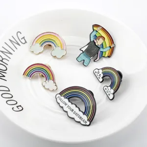 Dettaglio di cinque spille colorate in smalto arcobaleno su un piatto di ceramica