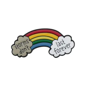 Primo piano dettagliato di una spilla smaltata arcobaleno con testo motivazionale