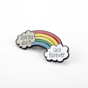 Dettaglio spilla in smalto arcobaleno con scritta motivazionale storms don't last forever