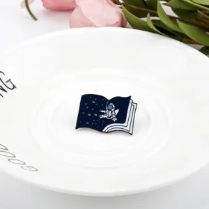 Close-up of a cartoon astronaut book enamel pin on a white plate with flowers