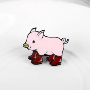 Close-up detail of a whimsical pink pig enamel pin wearing stylish red boots accessory