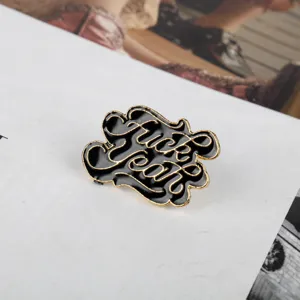 Nahaufnahme einer Punk-Emaille-Nadel mit Fuck-Yeah-Text in Gold und Schwarz