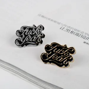 Detail der Punk-Emaille-Pins mit 'Fuck Yeah'-Schriftzug auf Gold- und Silbermetall