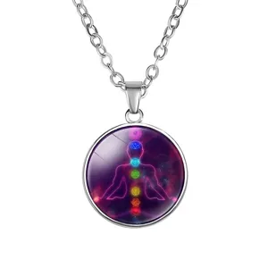 Close-up of silver yoga pendant necklace with 7 chakra symbols and nebula background.