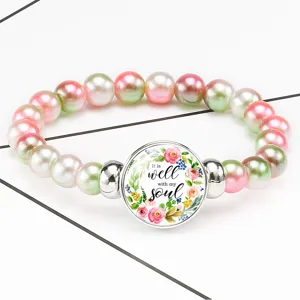 Macro detail of time gem charm on floral beaded elastic bracelet with soul quote
