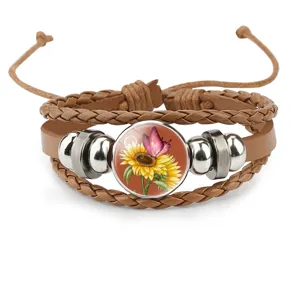 Close-up of brown leather bracelet with sunflower and butterfly glass cabochon design