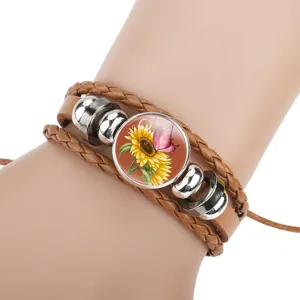 Close-up of a multi-layer brown braided leather bracelet with sunflower and butterfly charm.