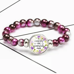 Detailed view of elastic beaded bracelet with floral quote cabochon pendant