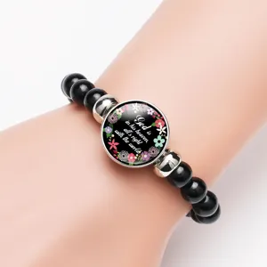 Detailed shot of a black beaded stretch bracelet with an inspirational quote charm