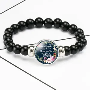Close-up of black beaded stretch bracelet featuring a Bible verse glass cabochon center
