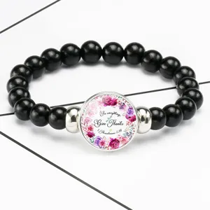 Close-up of Bible verse bracelet featuring floral pattern and Give Thanks quote