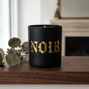 Nahaufnahme von gotischen NOIR Gold-Spiegel-Alphabet-Aufklebern auf schwarzer Kerze.