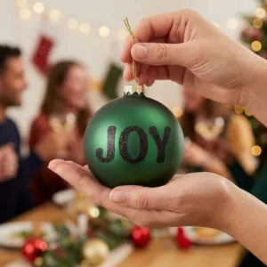 Close-up of black glitter letter stickers on a green Christmas ornament for holiday party decor.