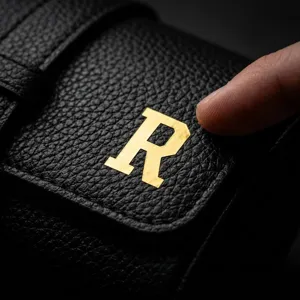 Close-up of a 0.5-inch shiny gold metallic alphabet sticker R on black leather
