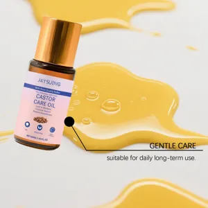 Macro view of Jaysuing castor oil bottle with golden oil splashes on white background.