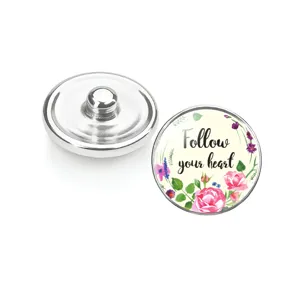 Détail du bouton pression en verre à motif floral avec texte "Follow your heart"