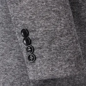 Detailed close-up of a premium grey herringbone blazer sleeve with four black buttons