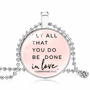 Detailed view of circular silver pendant featuring 1 Corinthians 16:18 quote on ball chain