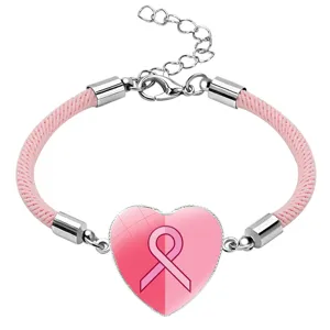 Close-up detail of a pink ribbon heart charm on a braided cord bracelet for awareness