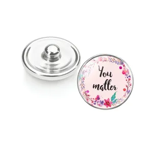 Détail du bouton pression en verre avec message 'You matter' et motif de fleurs.
