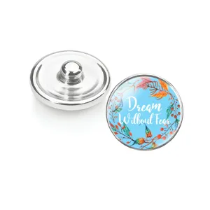 Détail d'un bouton pression en verre avec motif floral et texte Dream Without Fear