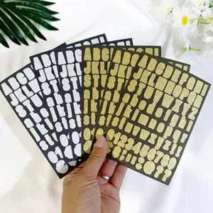 Macro view of gold and silver 1-inch glitter alphabet number stickers for DIY crafts.