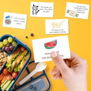 Détail d'une main tenant une carte de boîte à lunch avec des illustrations et des notes