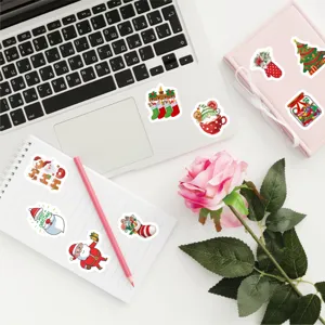 Christmas stickers applied on a laptop and notebooks with decorative pink rose and pencil