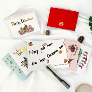 Close-up detail of Christmas card set with gold foil lettering and red envelope props