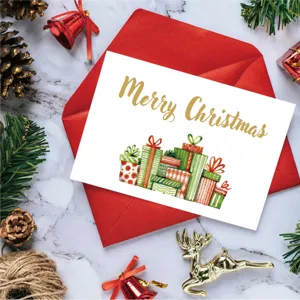 Close-up of gold foil Merry Christmas card with red envelope and festive props