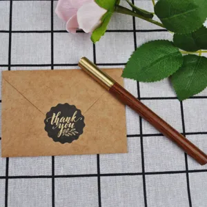 Macro detail of kraft paper envelope with Thank You seal and vintage wooden pen.