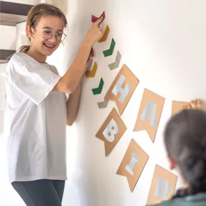Jeune fille appliquant des autocollants de lettres argentées sur une bannière en papier kraft