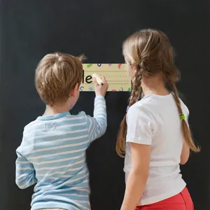 Two children writing on a colorful student name plate for classroom desk decoration
