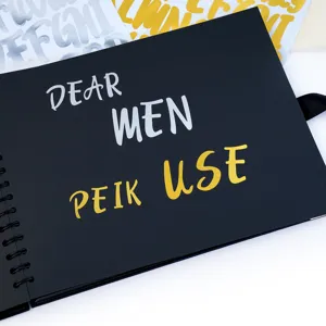 Detailed view of shiny gold and silver alphabet stickers applied on a black paper surface