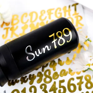 Close-up of gold and silver handwriting letter stickers applied on a black bottle