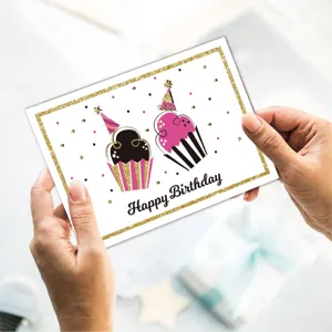 Close-up view of hands holding a minimalist Happy Birthday card with cupcake designs