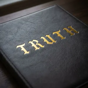 Makro-Detail von goldenen gotischen Alphabet-Aufklebern mit TRUTH auf schwarzem Leder.
