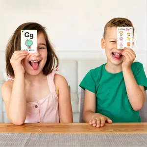 Zwei lächelnde Kinder halten pädagogische Englisch-Alphabet-Phonetik-Karten im Klassenzimmer