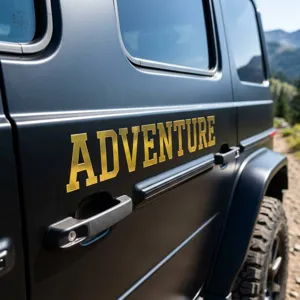 Close-up of golden metallic 'ADVENTURE' vinyl sticker on matte black car door