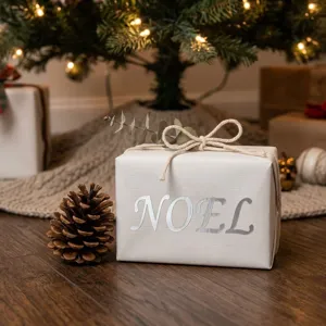 Detail eines silbernen Noel-Heißprägeaufklebers auf einem weißen Weihnachtsgeschenkkarton.