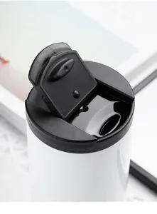 Detailed close-up showing the flip-top lid mechanism of a white stainless steel travel mug.