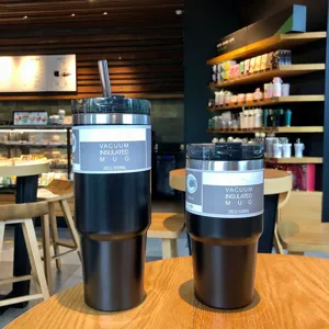 Pair of 30oz and 20oz black stainless steel vacuum insulated coffee mugs in a cafe.