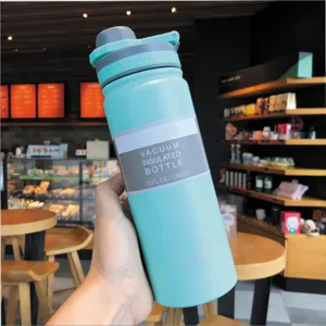 Close-up of a mint green vacuum insulated stainless steel water bottle in a cafe setting.