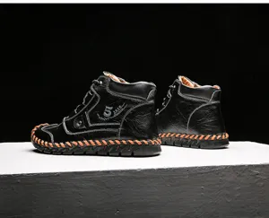 Detail view of handmade black leather boots with vibrant orange stitching and soft sole