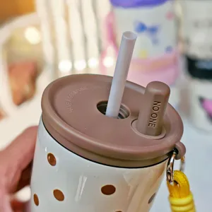Stainless steel insulated tumbler detail, close-up of brown lid, straw and yellow rope.