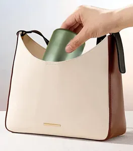 Detailed view of mini green stainless steel thermos cup being placed into a handbag