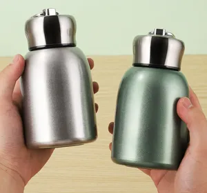 Close-up of portable mini stainless steel vacuum flasks in silver and green colors